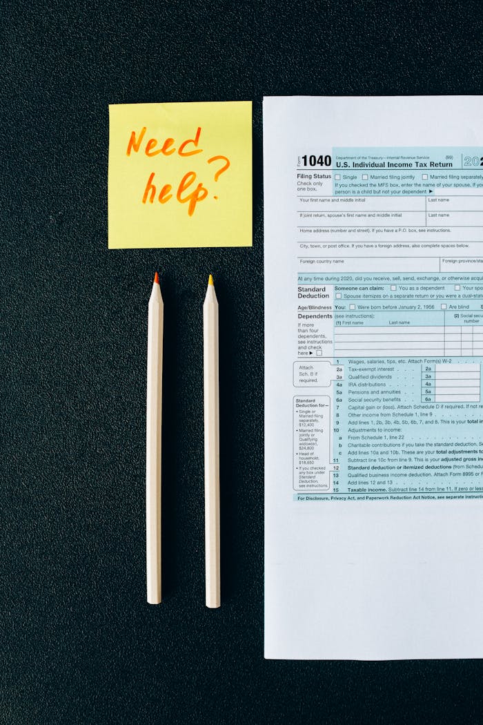 Services A tax form 1040 with a 'Need help?' sticky note and pencils on a black surface.