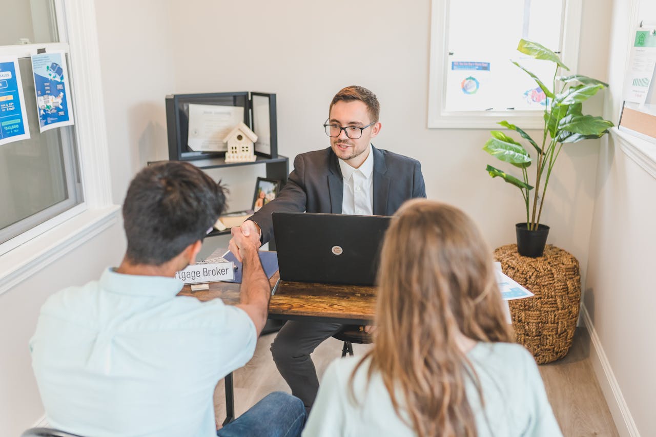Services Men and woman discussing mortgage with broker in a modern office setting.